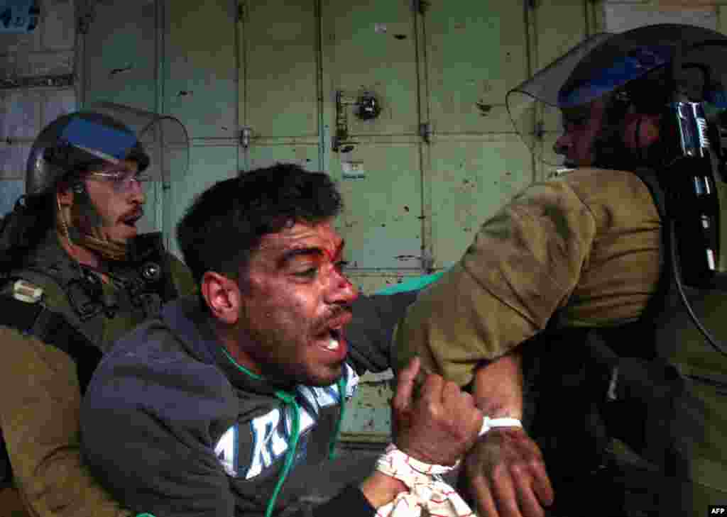 Demonstran Palestina melawan saat ditahan tentara Israel dalam bentrokan di kota tua Hebron, menyusul demonstrasi yang menuntut pembukaan kembali jalan Shuhada, yang dulu merupakan jantung kota. 