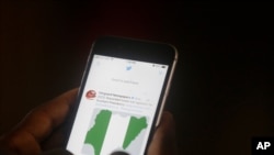 FILE - A man uses his mobile phone to read news on Twitter inside an office in Lagos, Nigeria, June 7, 2021.