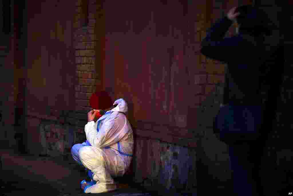 An emergency paramedic leans against a wall outside the Matei Bals hospital compound in Bucharest, Romania, where an early-morning fire killed four people, authorities said.