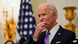 President Joe Biden pauses as he speaks about the coronavirus, accompanied by Vice President Kamala Harris, in the State Dinning Room of the White House, Jan. 21, 2021, in Washington. 