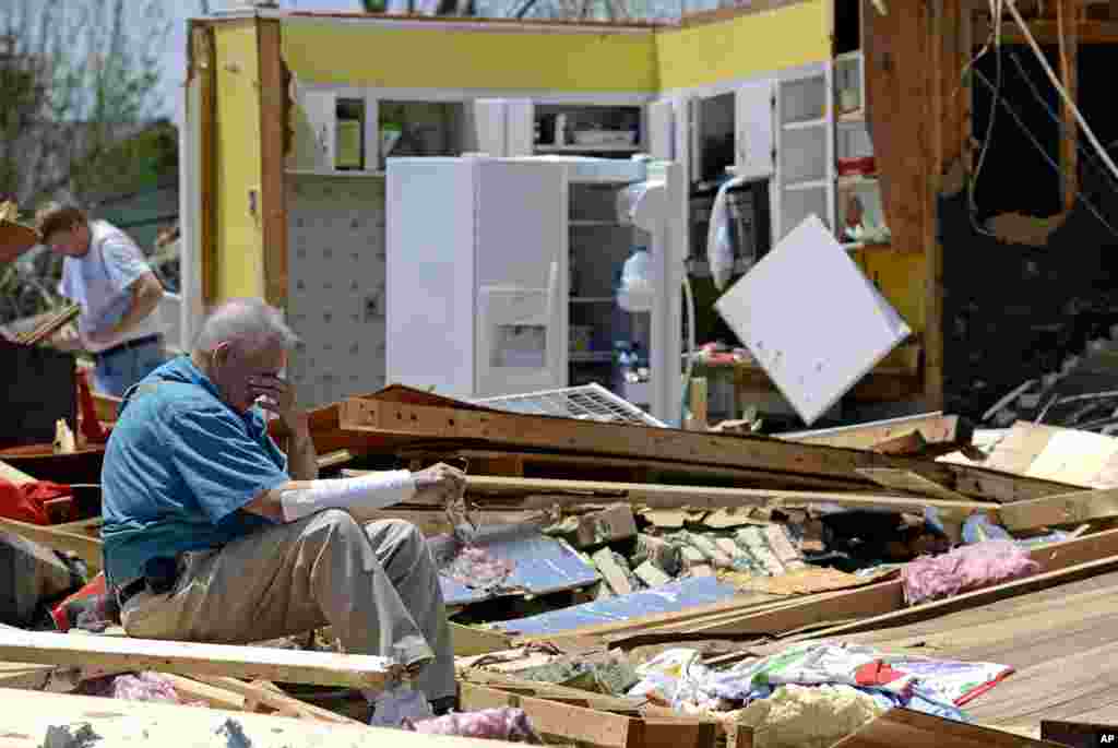 Charles Milam mencari barang-barangnya di antara reruntuhan rumahnya yang hancur akibat tornado di kota Tupelo, negara bagian Mississippi, AS. 