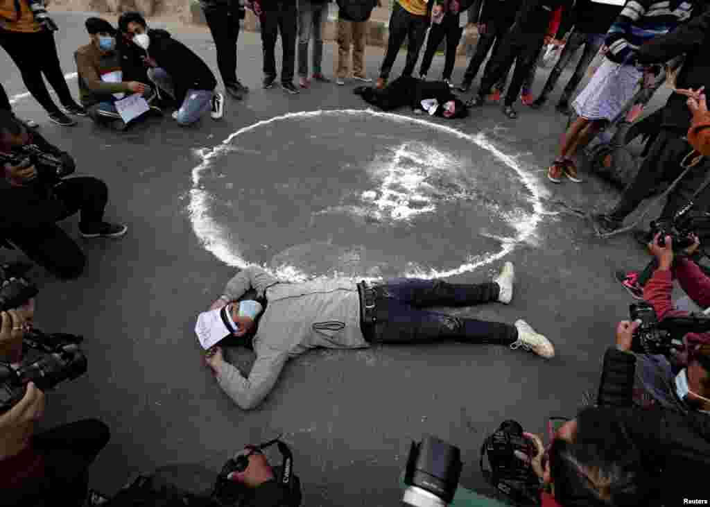 Protesters lie down on the road next to the Nepalese word that means parliament during a protest against the dissolution of parliament, in Kathmandu, Nepal.