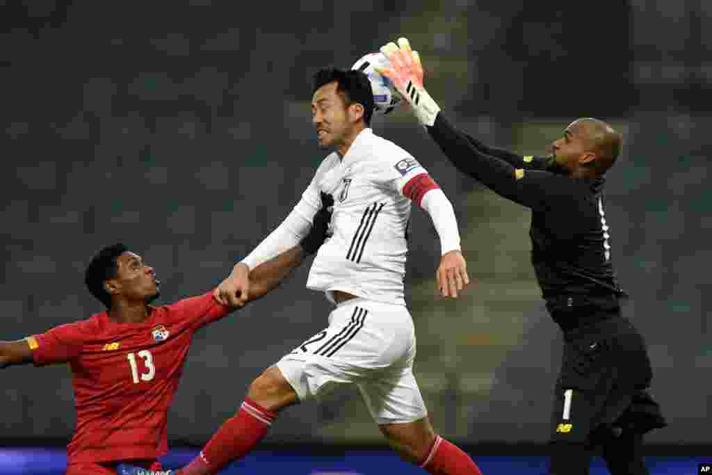 Japan's Maya Yoshida, center, jumps for the ball as Panama's goalkeeper Luis Me Jia, right, makes a save and Oscar Linton pushes him during the international friendly soccer match between Japan and Panama at Merkur-Arena stadium in Graz, Austria.