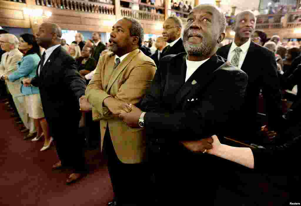 Kasisi Richard Harkness akishikana mkono na Kasisi Jack Lewin (2ndR) wanapoimba wimbo wa "We Shall Overcome" mwishoni mwa sala ya makumbusho katika kanisa la Morris Brown AME, Charleston, South Carolina, June 18, 2015.