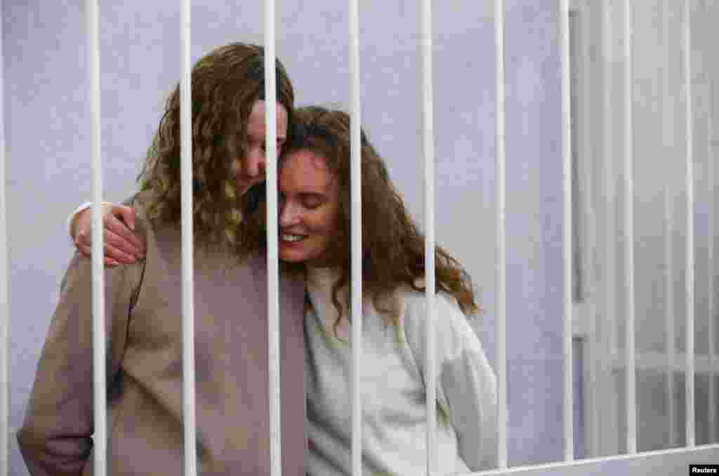 Yekaterina Andreeva and Darya Chultsova, journalists working for the Polish television channel Belsat accused of coordinating mass protests in 2020 by broadcasting live reports, embrace inside a defendants' cage during a court hearing in Minsk, Belarus.