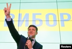 FILE - Ukrainian comic actor and presidential candidate Volodymyr Zelenskiy flashes a victory sign following the announcement of the first exit poll in a presidential election at his campaign headquarters in Kyiv, Ukraine, March 31, 2019.