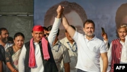 Indian National Congress (INC) Party leader Rahul Gandhi (2R) and Samajwadi Party President Akhilesh Yadav (C) gesture as they arrive to attend an election rally of Indian National Developmental Inclusive Alliance (INDIA) on the outskirts of Varanasi on M
