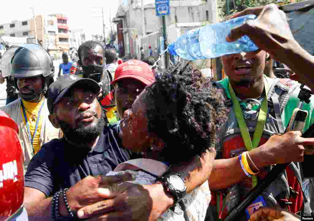 Journalists help a colleague who fainted after police threw tear gas during a protest against Haiti's President Jovenel Moise, in Port-au-Prince, Feb. 10, 2021.
