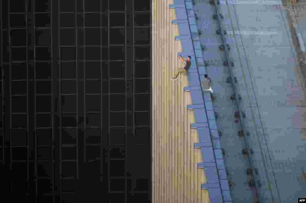 Two men take a series of selfies as they sit on the ledge of a high-rise building in an activity called "rooftopping" in Hong Kong, Aug. 23, 2016.