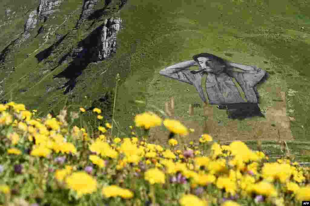 Lukisan 'ramah lingkungan' karya pelukis Perancis Saype di lokasi ski Chaux-de-Mont, pegunungan Alpen, Swiss.