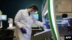 ROCKVILLE, MARYLAND - AUGUST 05: Lab Technician Carter Tavaglione loads at Janus G3 automated workstation with coronavirus test samples at Advagenix, a molecular diagnostics laboratory, on August 05, 2020 in Rockville, Maryland. An advanced genetics…