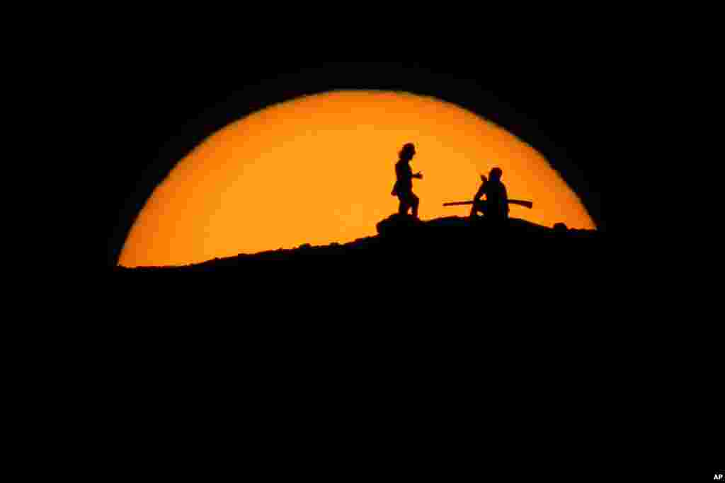 Hikers watch the sunset from a peak at Papago Park, Feb. 20, 2021, in Phoenix, Arizona.