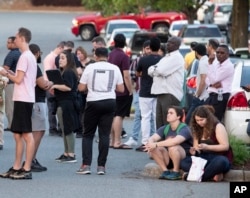 People gather across from the campus of UNC Charlotte after a shooting incident at the school, April 30, 2019, in Charlotte, N.C.