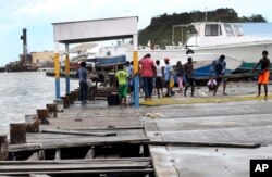Personas en St. John, Antigua y Barbuda recuperan partes de un muelle que se rompió tras el paso del huracán Irma. Sept. 6, 2017.