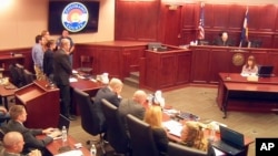 In this image taken from video, accused Colorado theater shooter James Holmes, standing on the far left, listens as the verdict is read during his trial, in Centennial, Colorado, July 16, 2015. 