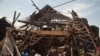 Men investigate the remains of a house struck hours earlier by deadly mortar fire, sparking angry protestors to take to the streets, in Goma, DRC, Aug. 24, 2013. 