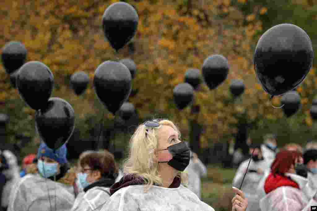 Medical workers hold black balloons in memory of those who lost their lives while in the care of the state health system in Bucharest, Romania. A fire last week at a hospital treating COVID-19 patients in northeastern Romania killed 11 people who were intubated in the intensive care unit.