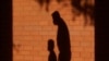 FILE - The shadows of a man and child are cast on a wall in Davie, Fla., Oct. 9, 2020. The proposed pandemic relief bill includes federal payments to families that the Center on Poverty and Social Policy said would cut the child poverty in half. 