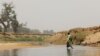 FILE - A Nigerian crosses the Yobe river separating Niger and Nigeria, at the Kukawa border in Damasak, Borno, Nigeria, Apr. 25, 2017. 