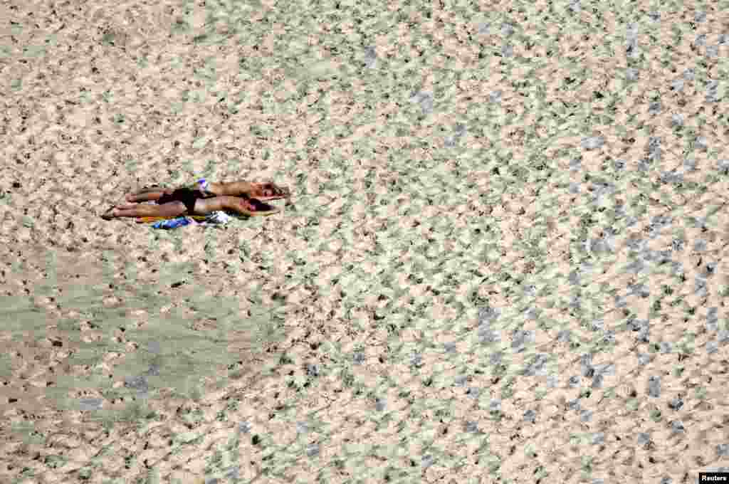 Women sunbathe on a warm, spring day at Sydney&#39;s Bronte Beach, Australia. 