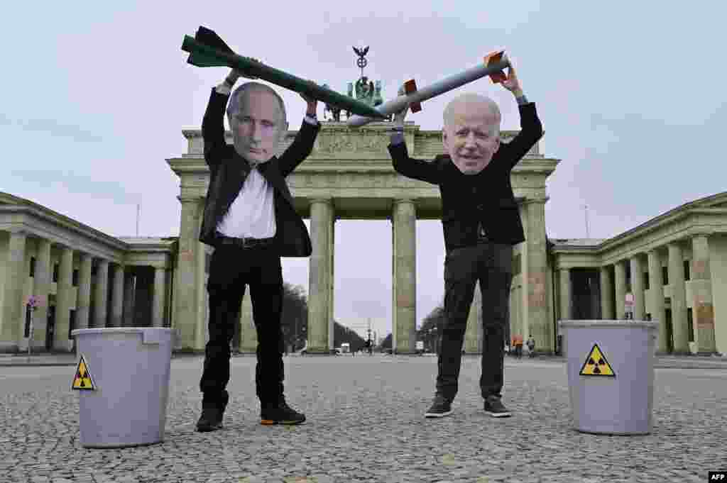 Peace activists wearing masks of Russian President Vladimir Putin, left, and U.S. President Joe Biden pose with mock nuclear missiles in front of Berlin's Brandenburg Gate in an action to call for more progress in nuclear disarmament.