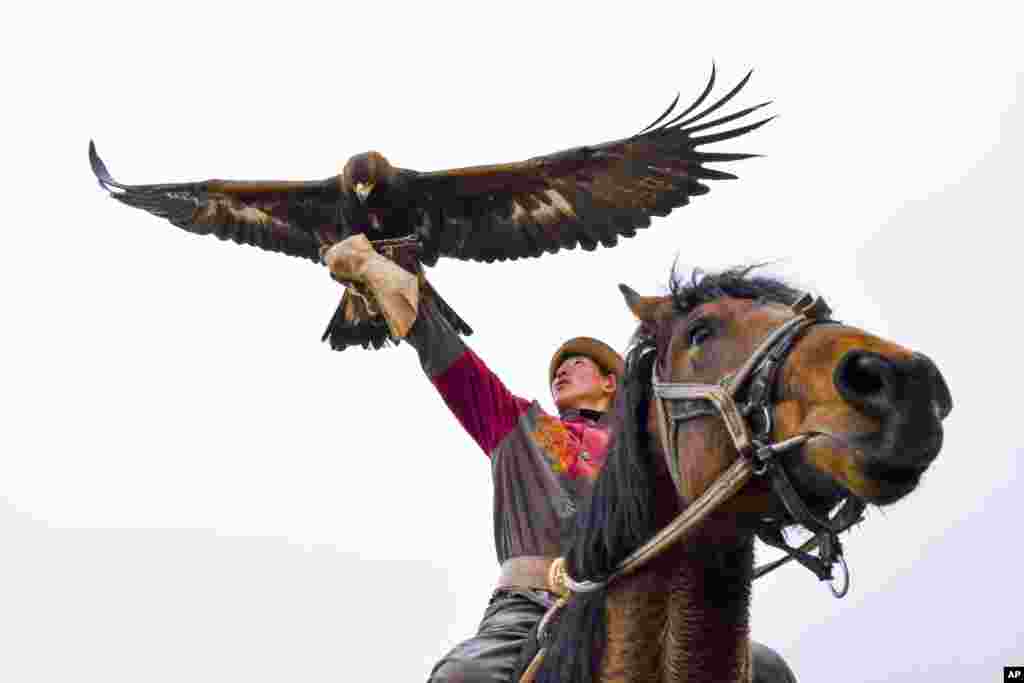 A man holding a golden eagle for an eagle hunt ride a horse during the hunting festival "Salburun" in Tuura-Suu, a small village nestled among the mountains, about 250 km. (156 miles) south-east of Bishkek, Kyrgyzstan.