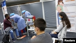 A man receives the first dose of the AstraZeneca COVID-19 vaccine as the Colombian government begins the vaccination campaign for people between 20 and 24 years old, in the newspaper library of the National University in Bogota, Aug. 15, 2021.