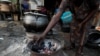 FILE - A woman arranges charcoal on an improvised cook stove in Ikeja, Lagos, Nigeria, Nov. 3, 2021.