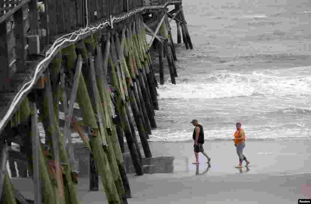 Para turis berjalan-jalan di Pantai Surfside, South Carolina, sebelum hujan dan bagian luar Badai Arthur bergerak mendekat (3/7). (Reuters/Randall Hill)