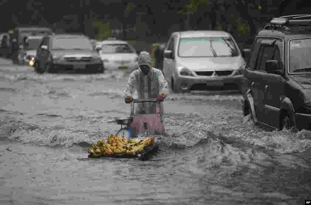 A banana vendor crosses a flooded street as southwest monsoon rains enhanced by Typhoon Usagi continue in Manila, Philippines, Sept. 22, 2013.