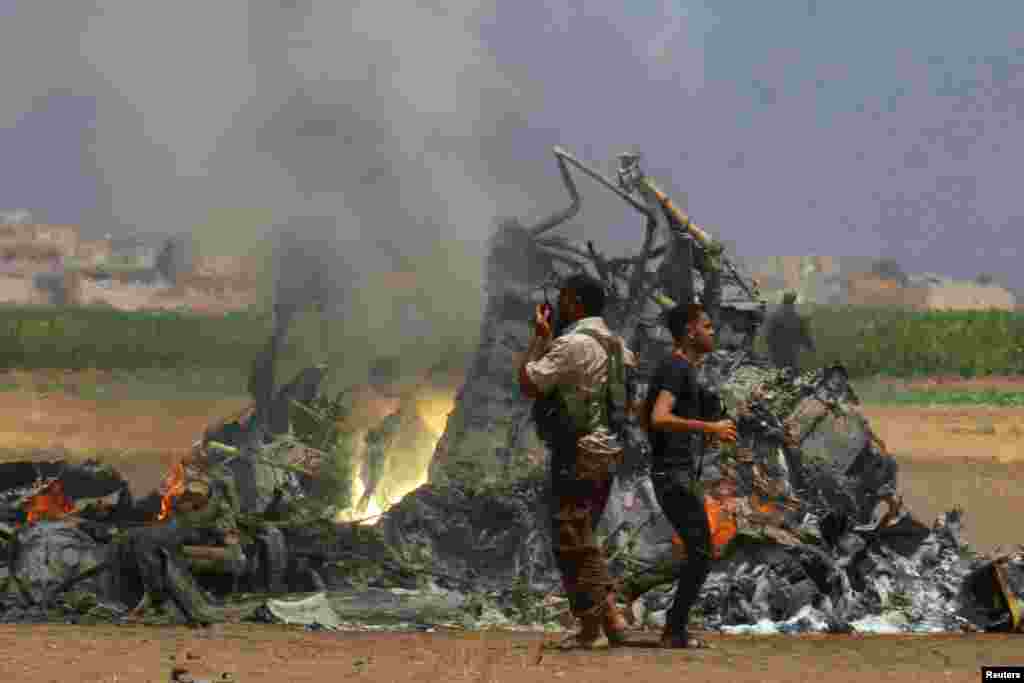 Dua pria memeriksa lokasi jatuhnya pesawat helikopter Rusia yang ditembak jatuh di provinsi Idlib, Suriah utara.