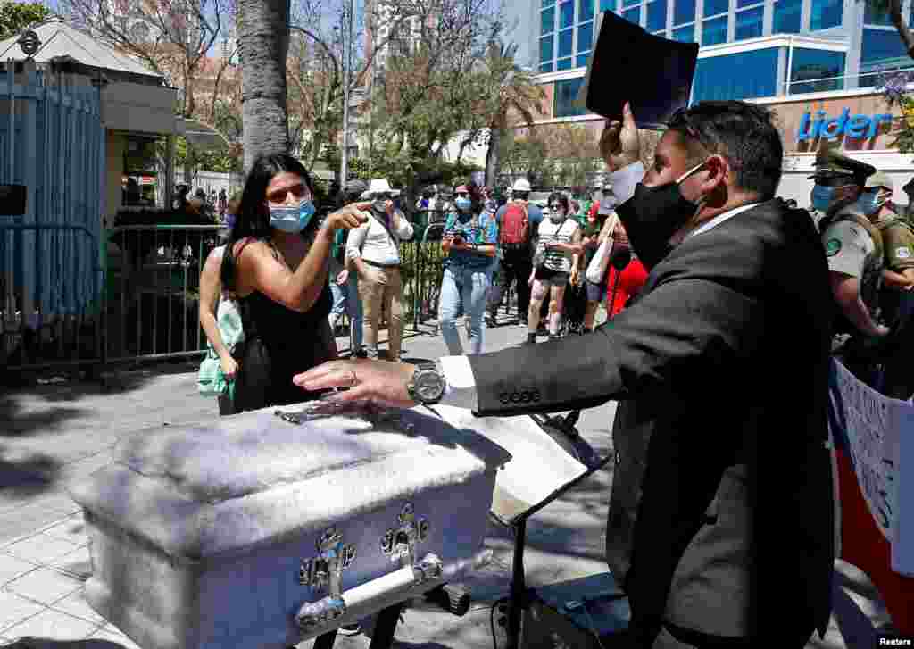 A preacher holds a bible next to an empty child's coffin as a pro-choice activist reacts, outside Congress where lawmakers will begin to discuss a bill that decriminalizes abortion until the 14th week of gestation, in Valparaiso, Chile, Jan. 13, 2021.