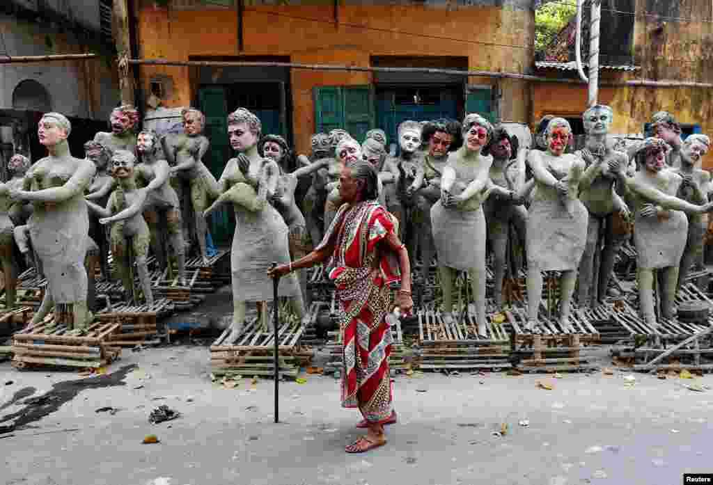 Seorang perempuan melewati patung-patung yang belum selesai dari karakter mitologi Hindu 'Dakinis' dan 'Yoginis,' menjelang perayaan festival keagamaan 'Kali Puja' di Kolkata, India.
