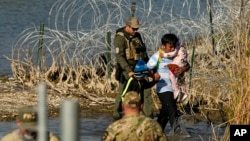 ARCHIVO - Migrantes son detenidos por funcionarios en la frontera entre Texas y México, el 3 de enero de 2024, en Eagle Pass, Texas. 