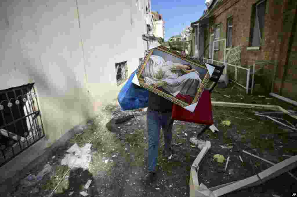 A man carries belongings from his damaged house two days after shelling by Armenian's artillery during fighting over the separatist region of Nagorno-Karabakh, in Ganja, Azerbaijan.