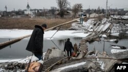 Жители украинского Бахмута пытаются пройти по разрушенному мосту. 1 февраля 2023г.