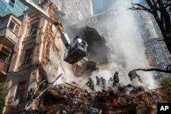 Kikosi cha zimamoto kikizima moto uliosababishwa na shambulizi la droni katika majengo kadhaa, Kyiv, Ukraine, Oct. 17, 2022.