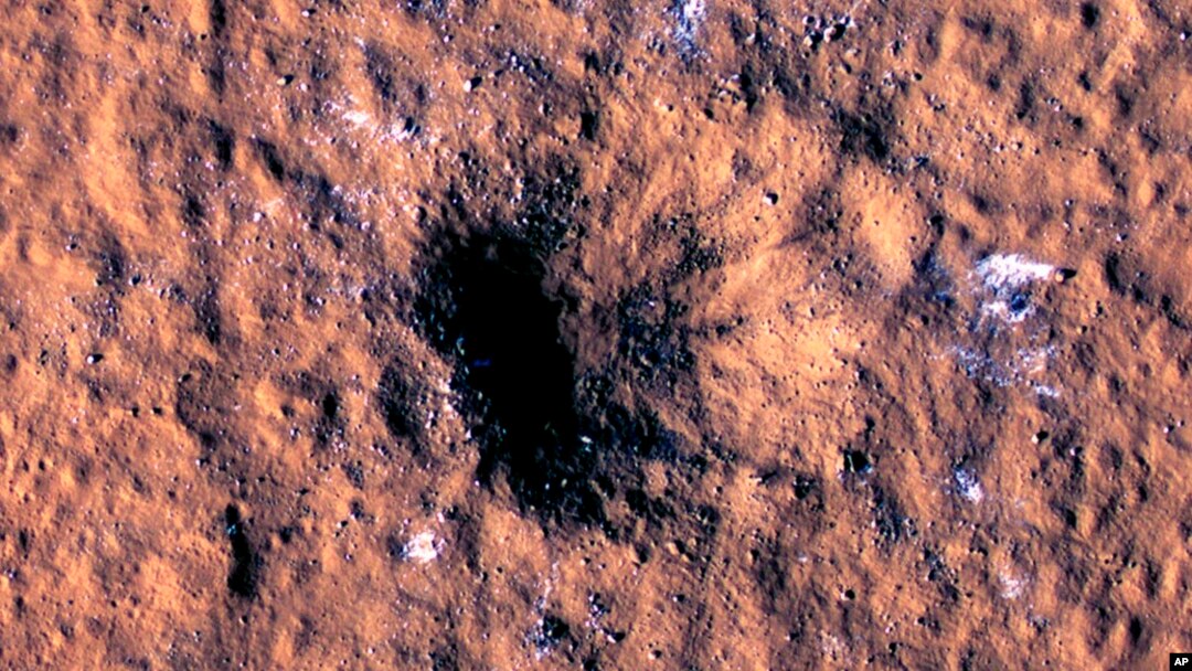 In this image made available by NASA on Thursday, Oct. 27, 2022, boulder-size blocks of water ice are seen around the rim of an impact crater on Mars. The crater was formed Dec. 24, 2021, by a meteoroid strike. (NASA/JPL-Caltech/University of Arizona via AP)