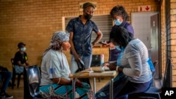 FILE - People are processed before receiving their COVID-19 vaccinations at the Orange Farm, South Africa, multipurpose center, Dec. 3, 2021.