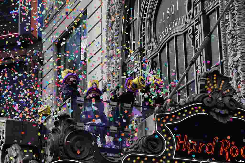 People stand on a balcony and 'flight test' some confetti ahead of the New Year's celebration in Times Square during the COVID-19 pandemic in the Manhattan borough of New York City.