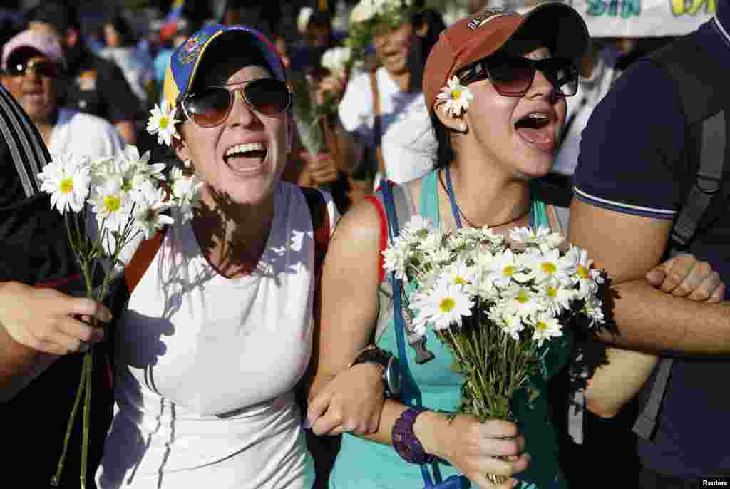 Supporters of opposition leader Leopoldo Lopez hold flowers and shout during a rally to promote peace in Caracas, Feb. 20, 2014.