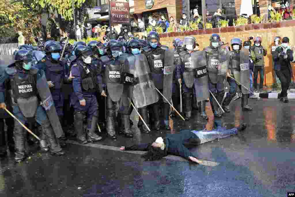 A protester from the civil society lies down in front of policemen during a demonstration against the dissolution of the country's parliament in Kathmandu, Nepal.