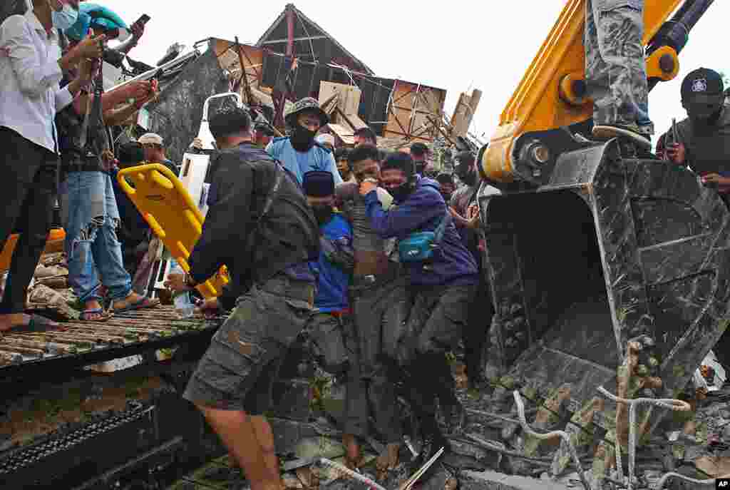 Rescuers assist a survivor pulled out from the ruin of a government building collapsed during an earthquake in Mamuju, West Sulawesi, Indonesia.