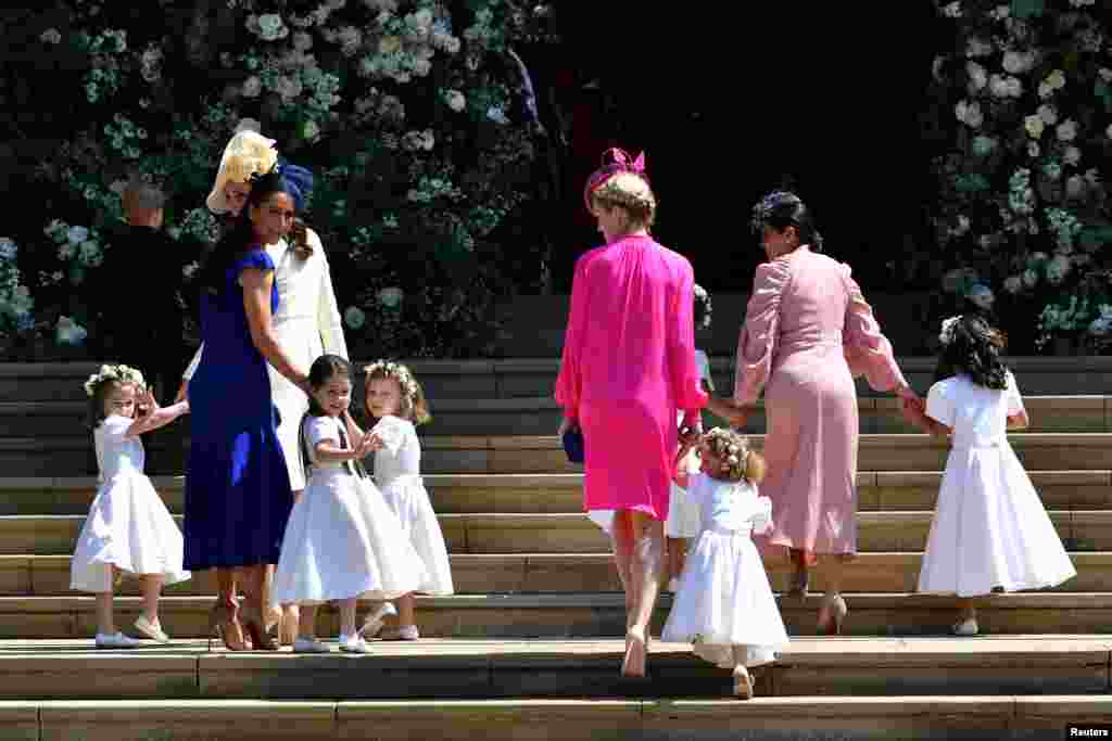 A duquesa britânica de Cambridge, Catherine, e a amiga de Meghan Markle, a estilista canadiana Jessica Mulroney, seguram as anjinhas à porta da capela de S. George no castelo de Windsor, onde o príncipe Harry e Meghan Markle se casaram. 19 de Maio de 2018