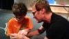 Magician Kevin Spencer teaches Liam Shannon a magic trick, Oct. 4, 2014, Germantown, Maryland. (VOA/ J.Taboh)