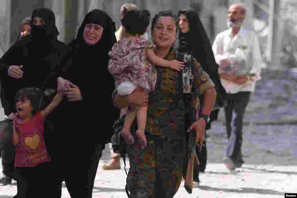 Seorang pejuang Pasukan Demokratik Suriah (SDF) membantu warga sipil yang dievakuasi dari kota Manbij yang dikuasai ISIS di Aleppo, Suriah (12/8). (Reuters/Rodi Said)