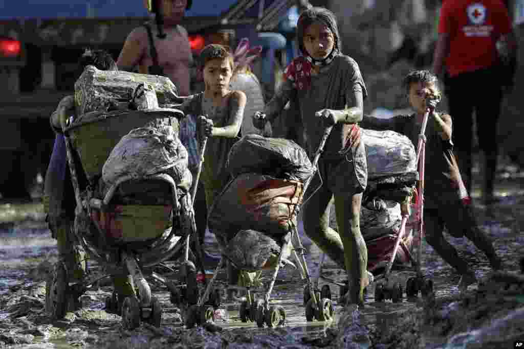 Children push baby strollers full of belongings they retrieved from their homes damaged by Typhoon Vamco in Rodriguez, Rizal province, Philippines.
