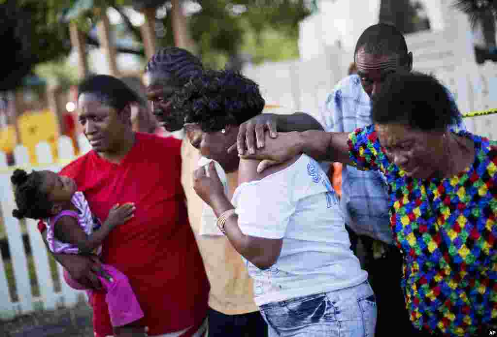 Gary and Aurelia Washington, center left and right, the son and granddaughter of Ethel Lance who died in Wednesday's shooting, leave a sidewalk memorial in front of Emanuel AME Church comforted by fellow family members Thursday, June 18, 2015.