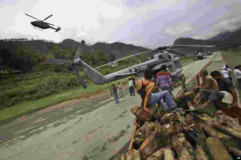 Locals unload wood from a truck to be loaded on to Indian Air force helicopters, in Gauchar, Uttarakhand, India, June 25, 2013.