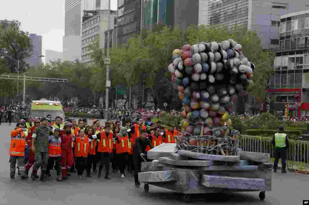 Rescue workers and volunteers that participated in rescue operations after the Sept. 19 earthquake, march behind a fist made out of safety helmets, as they lead the Day of the Dead parade on Mexico City's main Reforma Avenue, Oct. 28, 2017.